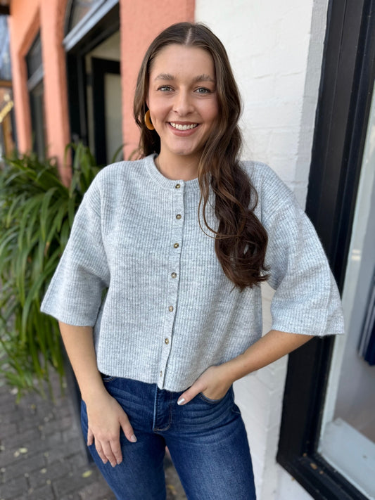Woman wearing a light blue textured shirt and jeans standing outdoors.