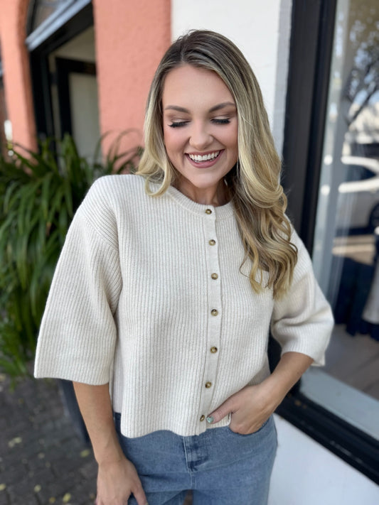 Woman wearing a cream ribbed sweater with buttons outdoors