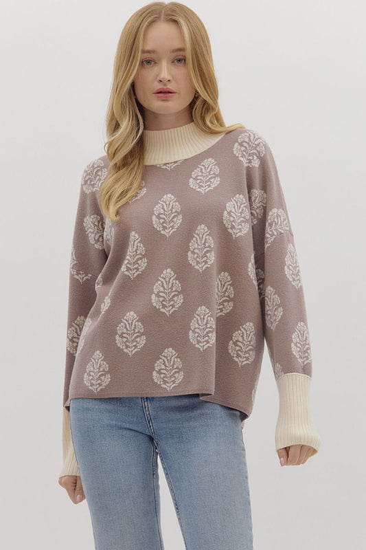 Woman wearing a patterned sweater and jeans on a plain background