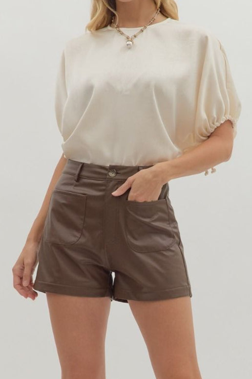 Brown shorts worn by a person on a plain background