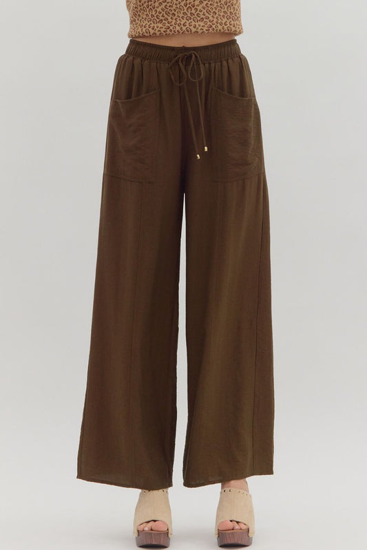 Brown wide-leg pants worn with a leopard print top on a white background