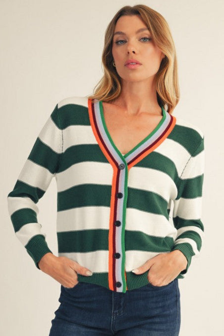 Woman wearing a green and white striped cardigan with colorful trim on a plain background
