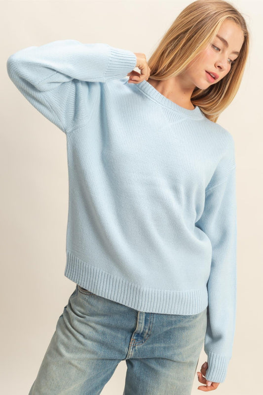 Woman wearing a light blue sweater and jeans against a beige background