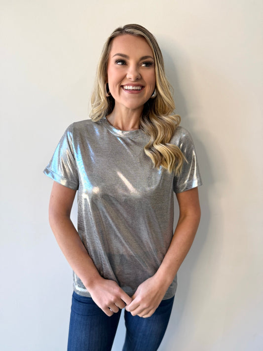 Woman wearing a silver metallic t-shirt against a plain background